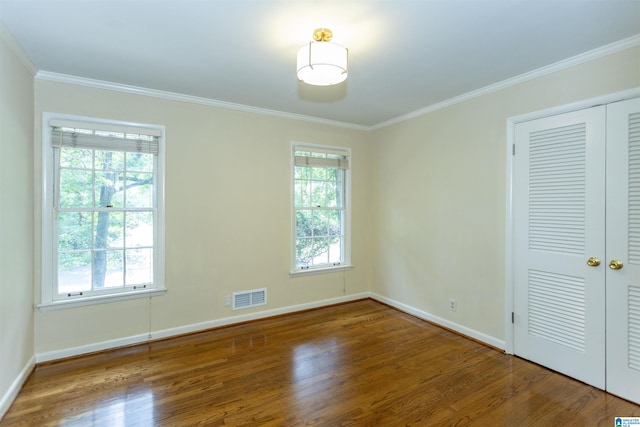 unfurnished bedroom featuring multiple windows, wood finished floors, and visible vents