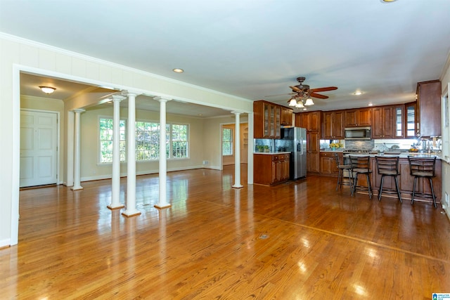 kitchen with ceiling fan, tasteful backsplash, decorative columns, stainless steel appliances, and hardwood / wood-style flooring