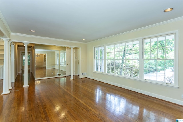 spare room with dark wood-type flooring, plenty of natural light, and ornate columns