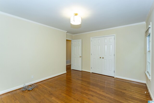 empty room with a notable chandelier, ornamental molding, and hardwood / wood-style flooring