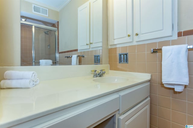 bathroom with visible vents, a tile shower, crown molding, vanity, and tile walls