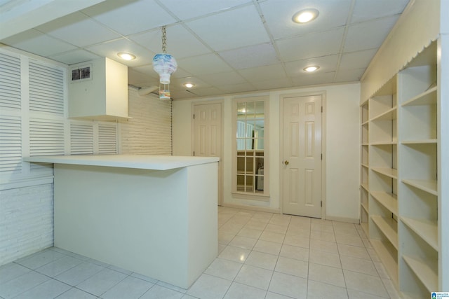 kitchen featuring light tile patterned floors, a peninsula, visible vents, hanging light fixtures, and light countertops