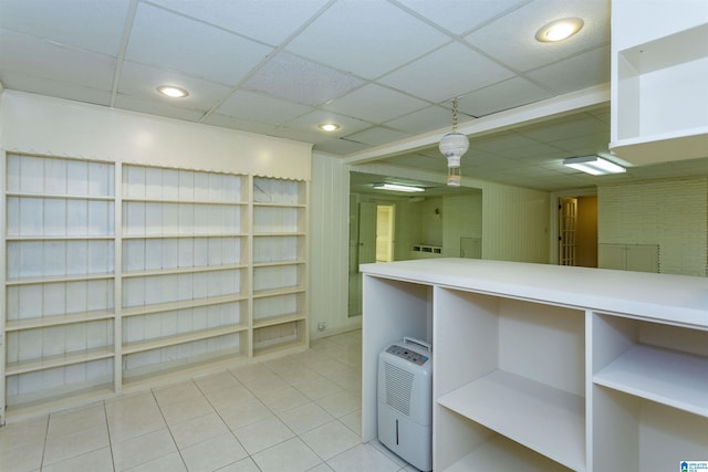 basement with light tile patterned floors, a paneled ceiling, and recessed lighting