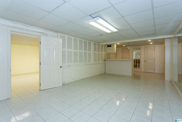 tiled empty room featuring a drop ceiling