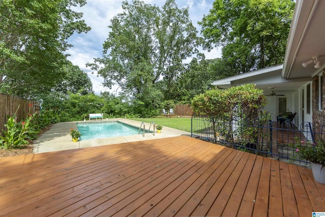 view of swimming pool with a wooden deck, a fenced in pool, a fenced backyard, ceiling fan, and a yard