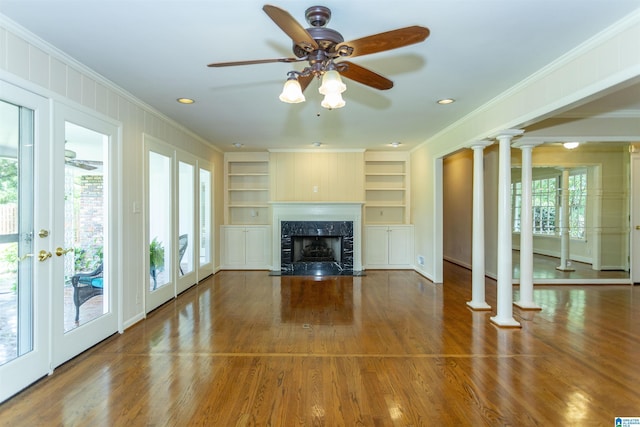 unfurnished living room with built in features, a fireplace, crown molding, and wood finished floors