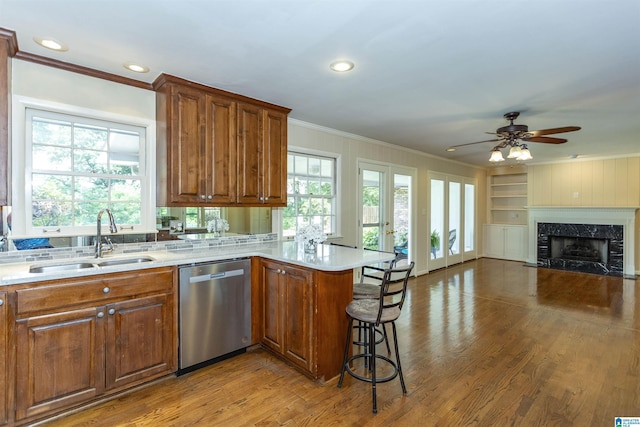 kitchen with a peninsula, a sink, open floor plan, stainless steel dishwasher, and a kitchen bar