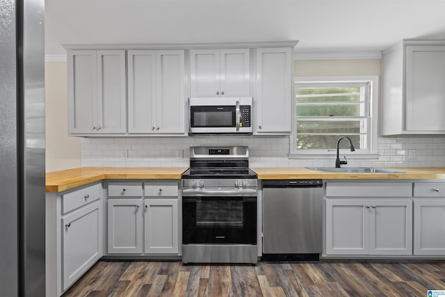 kitchen featuring butcher block counters, sink, appliances with stainless steel finishes, and tasteful backsplash