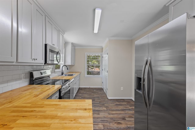 kitchen featuring wood counters, appliances with stainless steel finishes, tasteful backsplash, crown molding, and sink