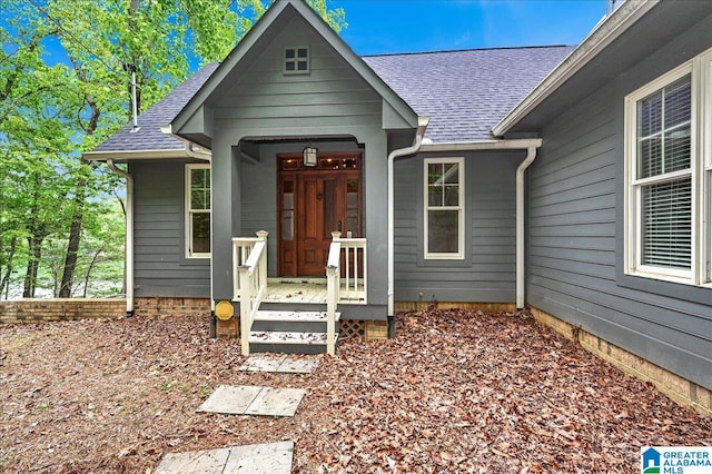 view of exterior entry with roof with shingles