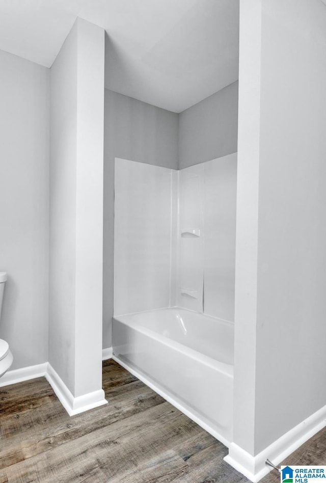 bathroom with bathtub / shower combination, hardwood / wood-style floors, and toilet