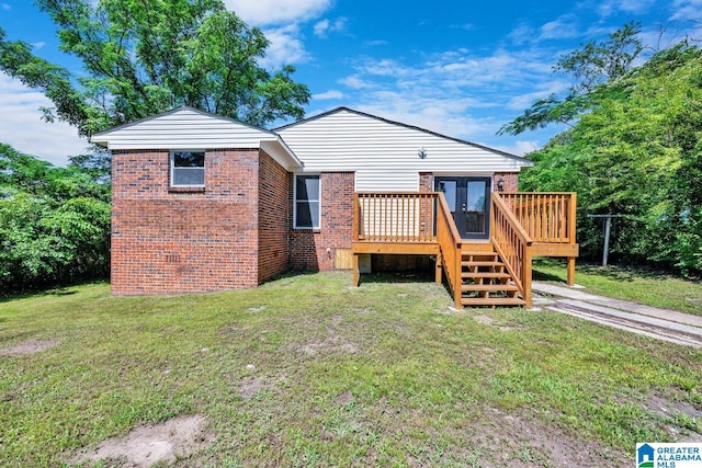 rear view of property featuring a yard and a wooden deck