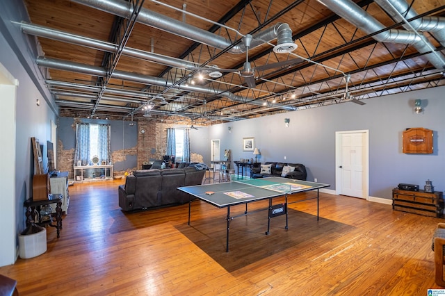 playroom featuring baseboards, a towering ceiling, hardwood / wood-style flooring, brick wall, and wood ceiling