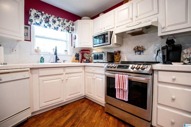 kitchen with backsplash, dark wood-type flooring, appliances with stainless steel finishes, and white cabinetry