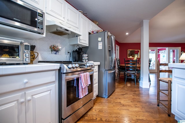 kitchen featuring light hardwood / wood-style floors, stainless steel appliances, backsplash, white cabinetry, and lofted ceiling