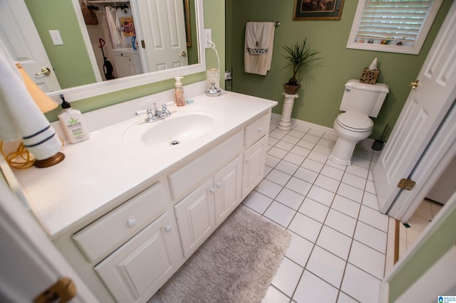 bathroom with tile flooring, vanity, toilet, and washer / clothes dryer