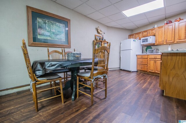 dining room featuring a paneled ceiling and dark hardwood / wood-style flooring