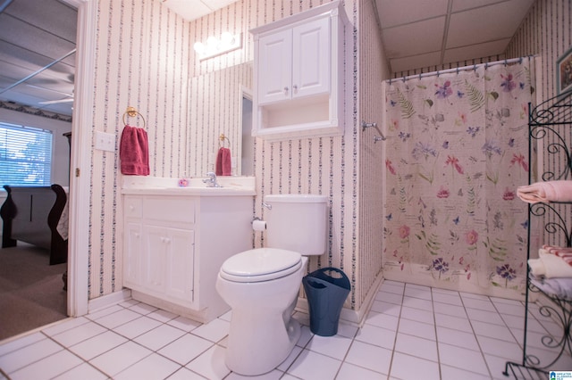 bathroom with tile floors, a paneled ceiling, vanity, and toilet