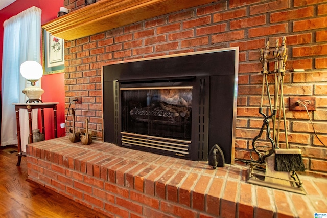 room details featuring a brick fireplace and wood-type flooring