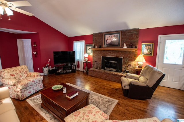 living room featuring brick wall, lofted ceiling, dark hardwood / wood-style flooring, a brick fireplace, and ceiling fan