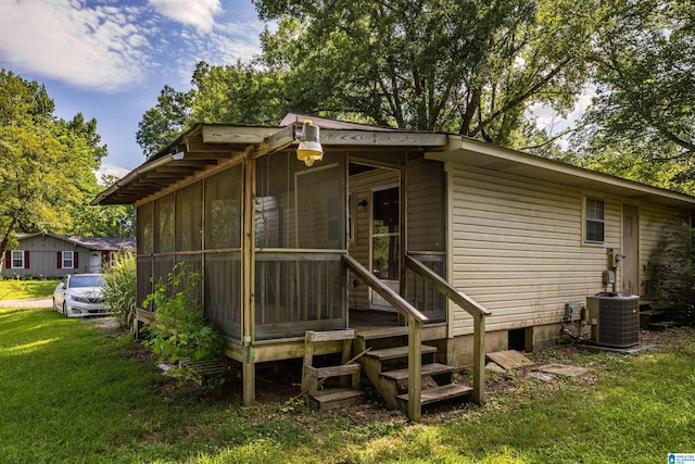 rear view of property with a yard, a sunroom, and central air condition unit