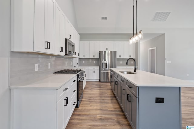 kitchen with decorative light fixtures, white cabinets, sink, and stainless steel appliances