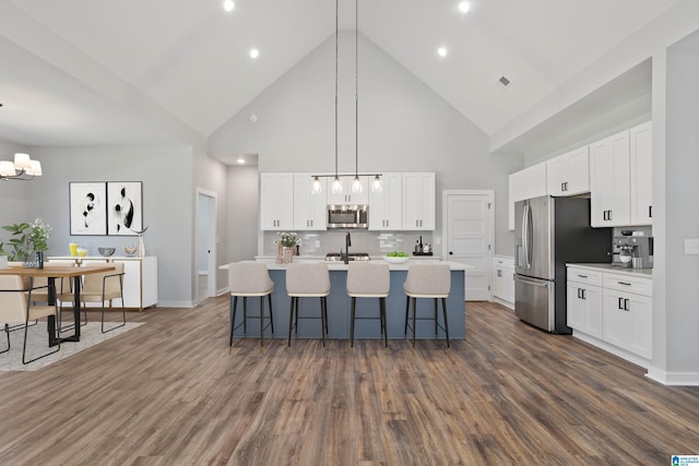 kitchen with appliances with stainless steel finishes, pendant lighting, white cabinets, and high vaulted ceiling