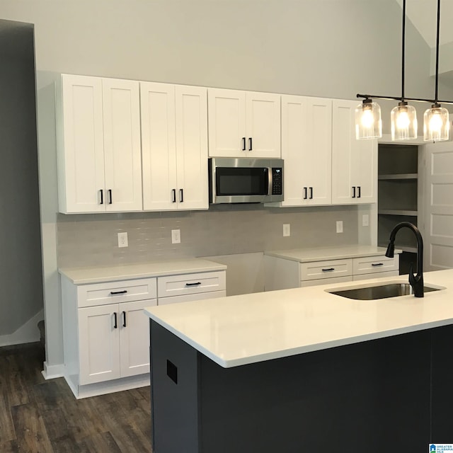 kitchen with pendant lighting, white cabinets, dark hardwood / wood-style flooring, sink, and high vaulted ceiling