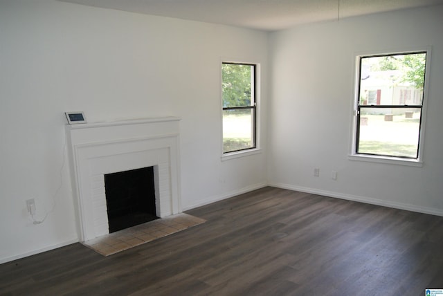 unfurnished living room featuring a wealth of natural light, a fireplace, and dark hardwood / wood-style floors