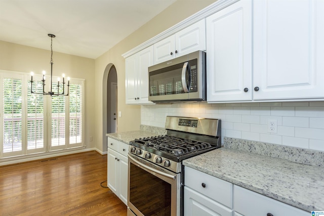 kitchen featuring tasteful backsplash, light stone counters, stainless steel appliances, white cabinets, and plenty of natural light