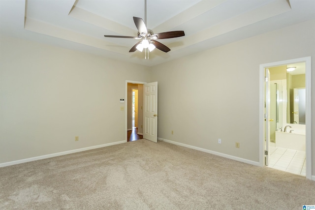 empty room with ceiling fan, a raised ceiling, and light colored carpet