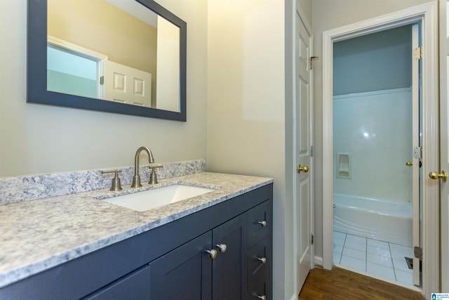 bathroom with a tub to relax in, vanity, and wood-type flooring