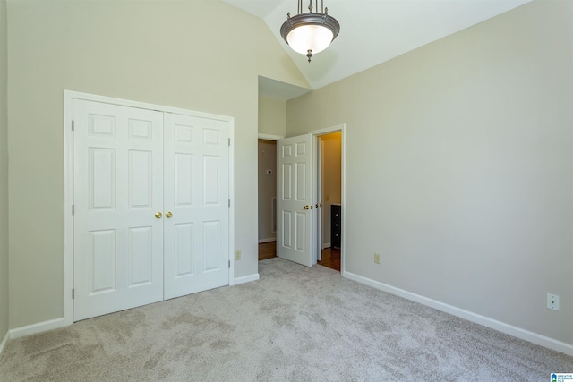 unfurnished bedroom featuring light carpet, a closet, and vaulted ceiling