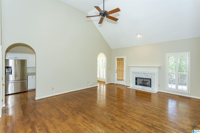 unfurnished living room with a high end fireplace, ceiling fan, dark hardwood / wood-style flooring, and high vaulted ceiling