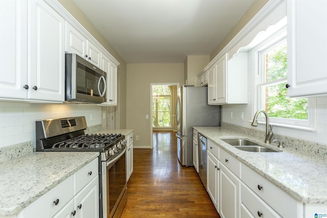 kitchen with light stone countertops, appliances with stainless steel finishes, dark hardwood / wood-style flooring, sink, and white cabinets