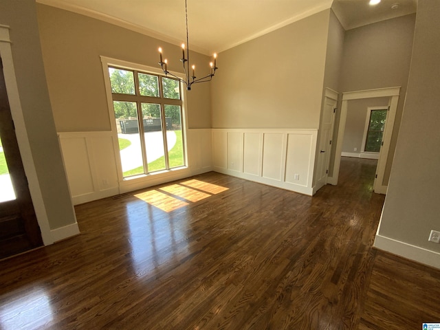 empty room featuring a notable chandelier, dark hardwood / wood-style floors, and ornamental molding