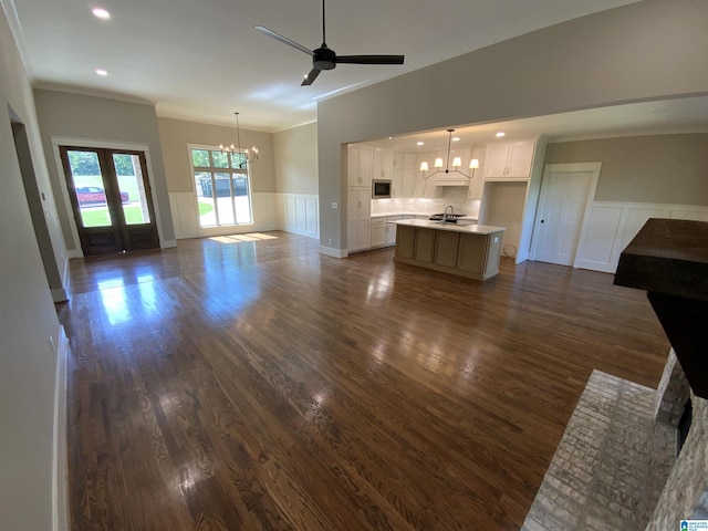 unfurnished living room featuring french doors, sink, dark hardwood / wood-style flooring, crown molding, and ceiling fan with notable chandelier