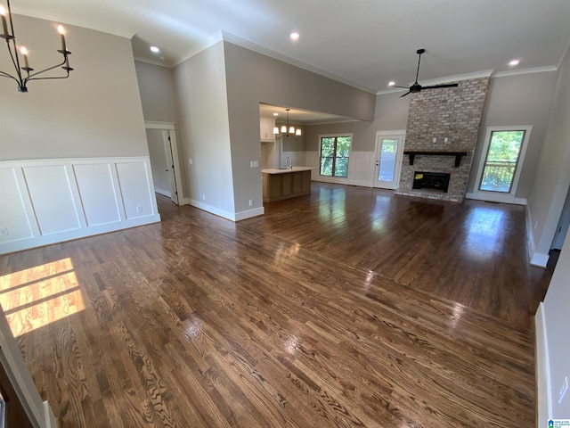 unfurnished living room featuring a wealth of natural light, a fireplace, dark wood-type flooring, and ornamental molding