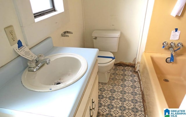 bathroom with a bath, vanity, and toilet