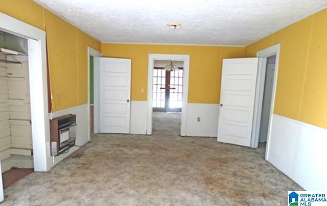 unfurnished living room with french doors, a textured ceiling, and heating unit