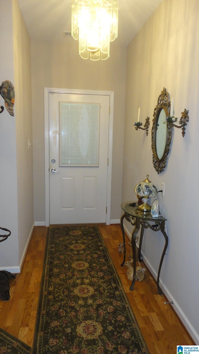 doorway to outside featuring an inviting chandelier and hardwood / wood-style floors