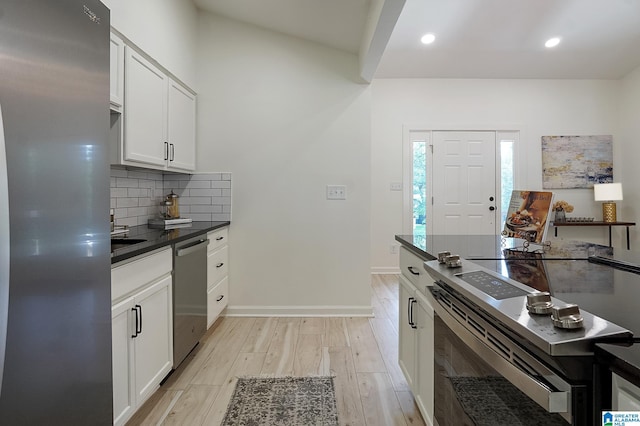 kitchen with backsplash, white cabinetry, light wood-type flooring, and appliances with stainless steel finishes