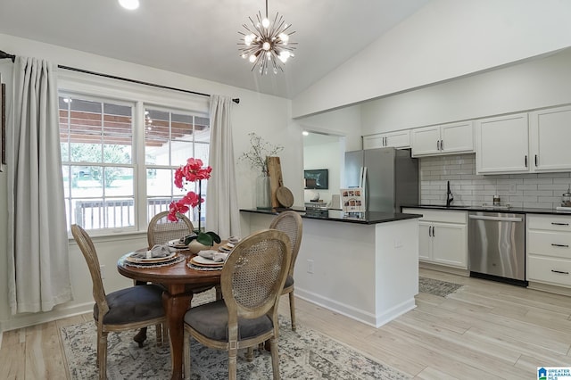 dining area featuring sink, lofted ceiling, light hardwood / wood-style flooring, and an inviting chandelier