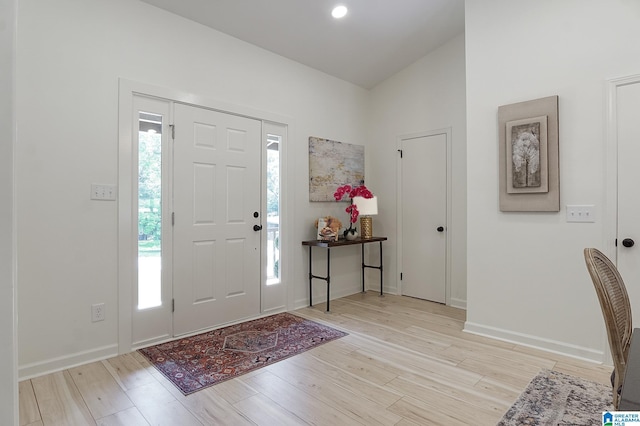 foyer entrance with light wood-type flooring, a wealth of natural light, and lofted ceiling