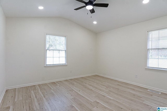 spare room featuring ceiling fan, lofted ceiling, a wealth of natural light, and light hardwood / wood-style flooring