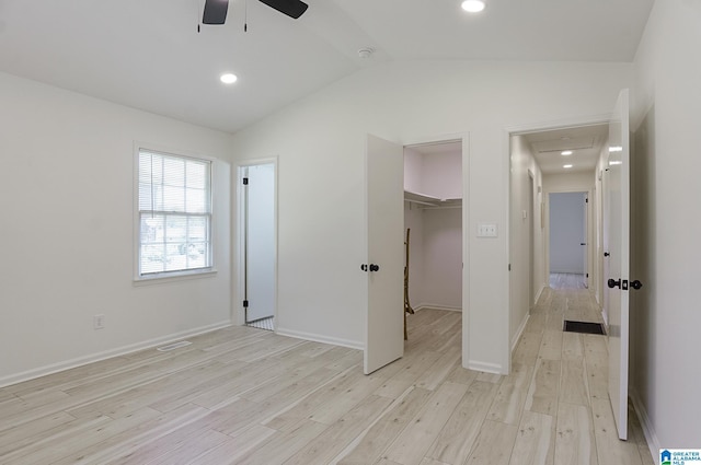 unfurnished bedroom with ceiling fan, a spacious closet, light hardwood / wood-style flooring, vaulted ceiling, and a closet