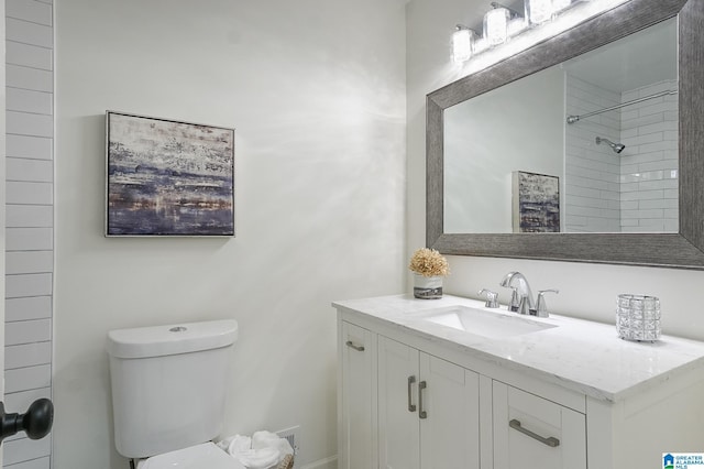 bathroom featuring vanity, toilet, and tiled shower