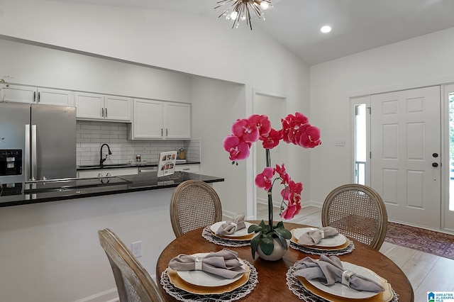 dining room with a chandelier, light hardwood / wood-style floors, vaulted ceiling, and sink