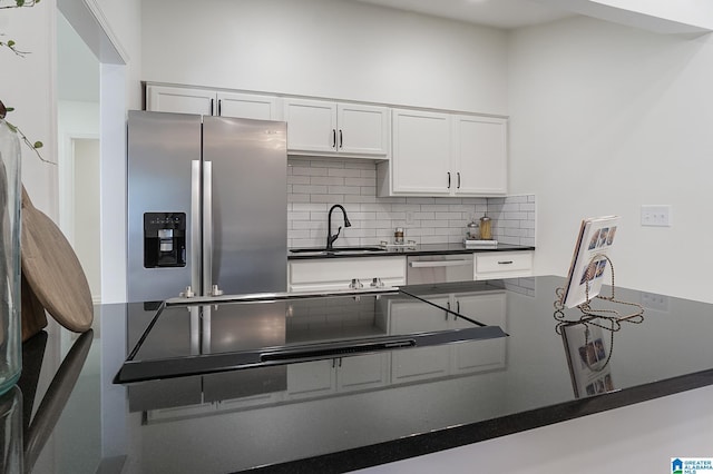 kitchen with white cabinetry, sink, backsplash, kitchen peninsula, and appliances with stainless steel finishes