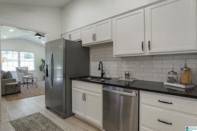 kitchen with white cabinets, stainless steel appliances, lofted ceiling, and sink